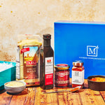 Assorted food items including a box labeled 'The Mediterranean Dish' on a wooden surface.