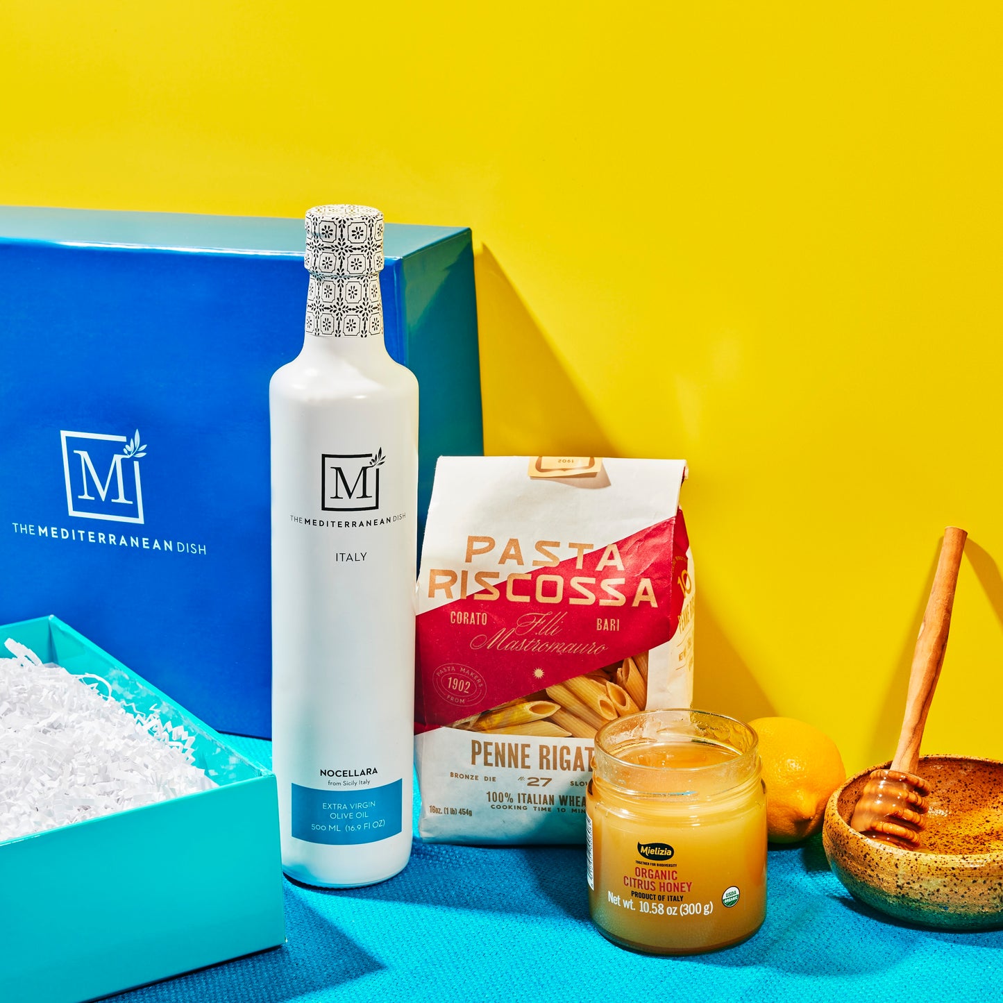 Pasta, olive oil, and other ingredients on a blue and yellow background with 'The Mediterranean Dish' branding.