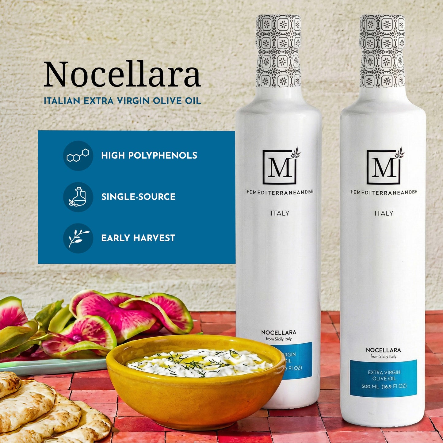 Two bottles of Nocellara Italian extra virgin olive oil with a bowl of salad and bread on a table.