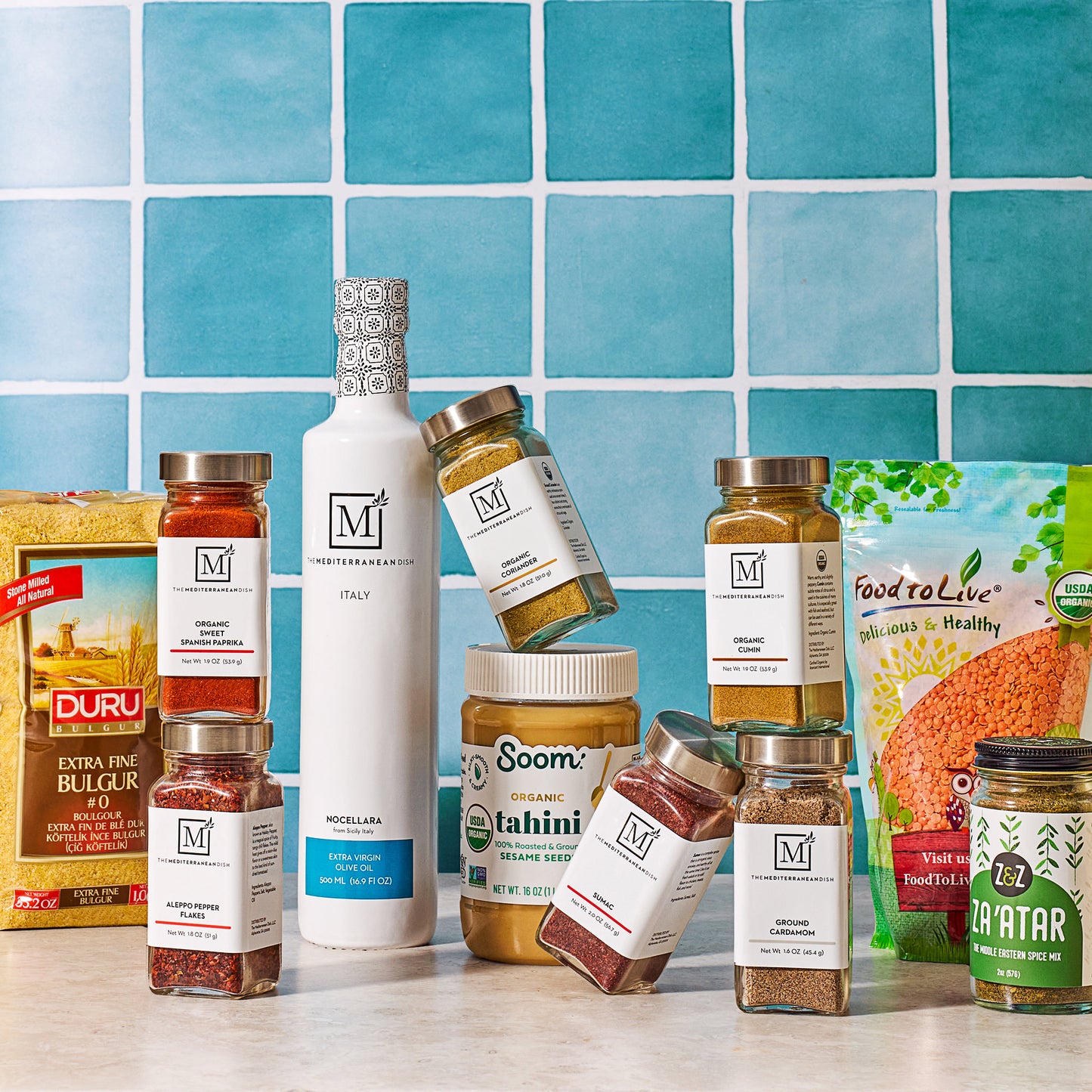 Assorted food products including bottles, jars, and boxes on a blue tiled background.