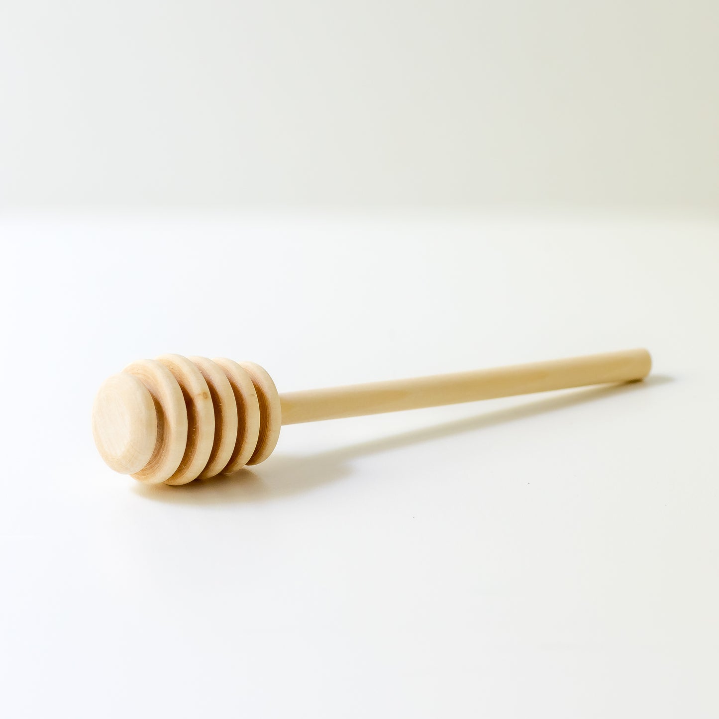 Wooden honey dipper on a white background