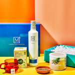 Assorted food products including olive oil, tea, and oregano on a colorful background with 'The Mediterranean Dish' branding.