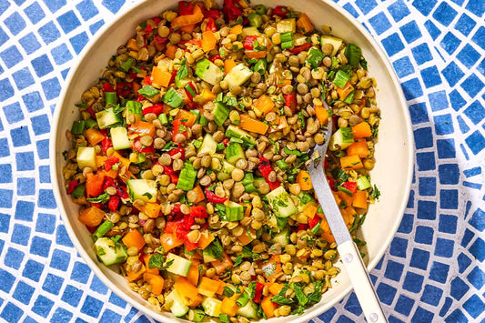 A close up of lentil salad in a serving bowl with a spoon.