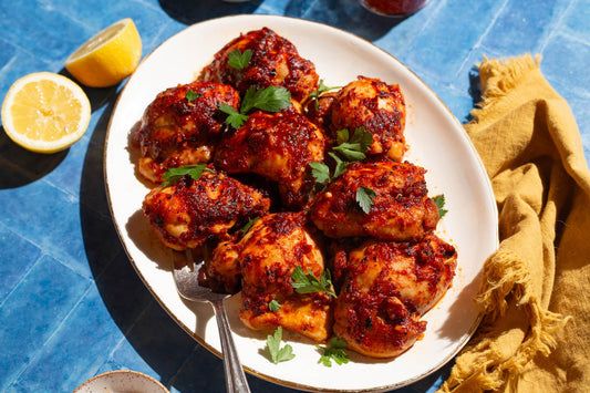 Glazed chicken thighs with a spicy-sweet harissa honey sauce, garnished with fresh herbs.