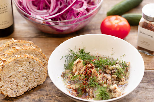 a close up of a sardine toast topped with cucumbers and pickled red onions.