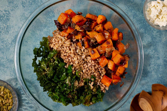 Butternut squash salad on a serving platter with gold serving utensils.