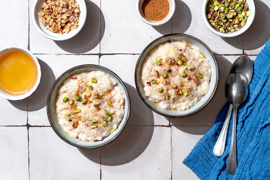 A close up of easy rice pudding garnished with pistachios, walnuts, cinnamon and a drizzle of honey.
