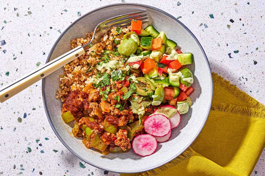 Spiced beef bowl with rice, fresh vegetables, and harissa oil drizzle.