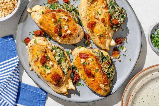 An overhead photo of four chicken breasts on a plate stuffed with a spinach mixture and topped with sun dried tomatoes.