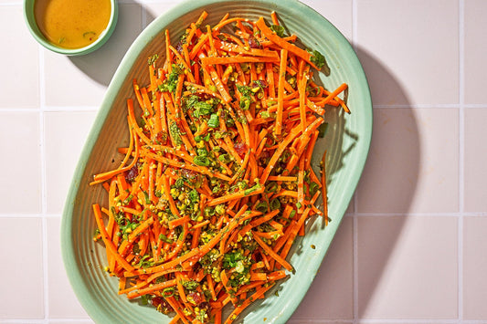 An overhead photo of a salad made up with shredded carrots and topped with herbs.