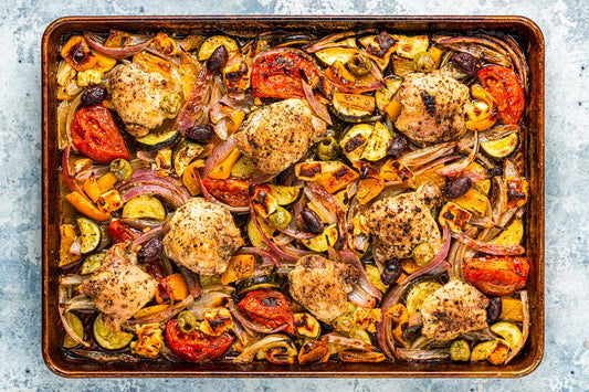 An overhead photo of a sheet pan filled with chicken thighs and roasted vegetables.