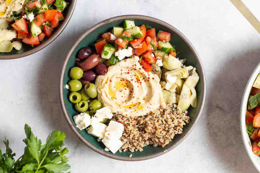 An overhead photo of a mediterranean bowl with quinoa with a fork in it.