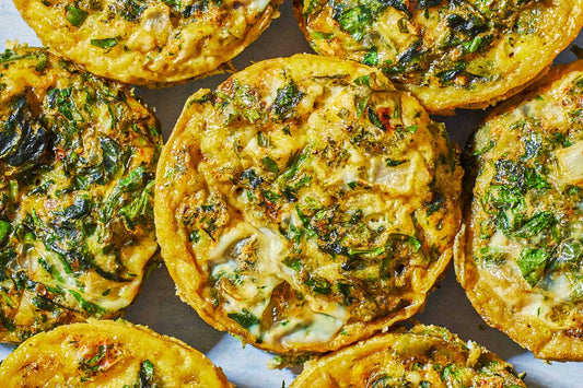 An overhead photo of a muffin tray filled with an egg mixture of egg, spinach, feta, and seasonings.