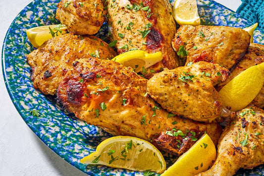 A plate of chicken wings garnished with fresh herbs and lemon wedges.