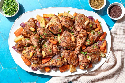 An overhead photo of a plate of chicken wings and thighs on top of an array of roasted vegetables.