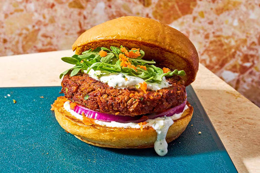 A lentil burger topped with fresh herbs and dripping with yogurt sauce.