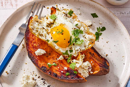 An overhead photo of a sweet potato topped with a fried egg and fresh herbs.