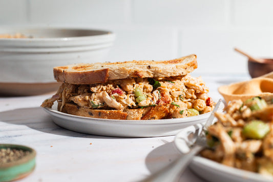 A chicken salad sandwich with toasted bread on top of a white plate.
