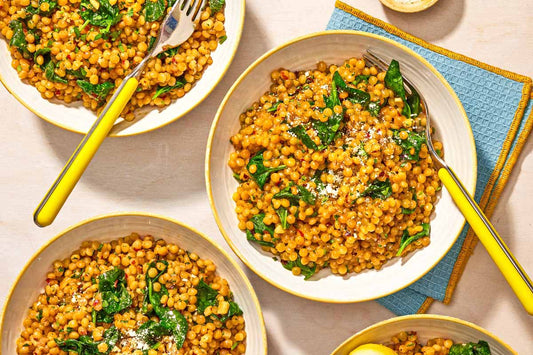 An overhead photo of three bowls of couscous topped with a fresh herb garnish. 