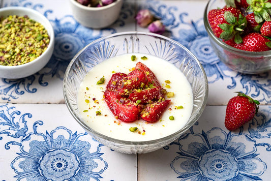 A glass bowl filled with milk pudding and topped with fresh strawberries.