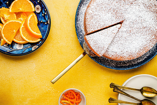 An overhead photo of a slice of cake cut being cut with a side of orange slices.