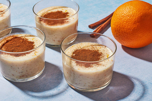 Three clear cups filled with rice pudding and topped with cinnamon.