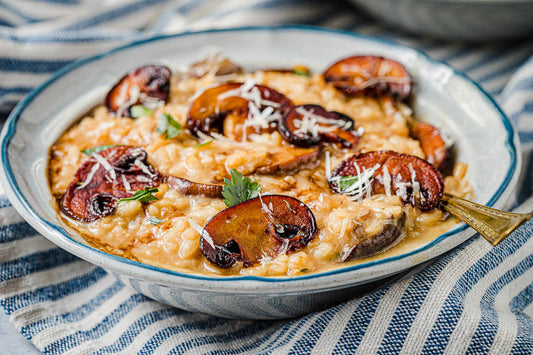 A bowl of risotto topped with sliced mushrooms and shredded parmesan cheese.