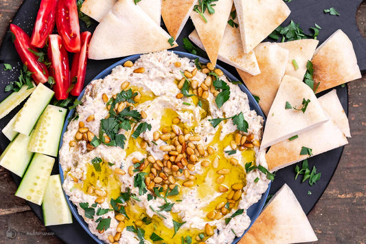 An overhead photo of a mezze platter with baba ganoush, fresh pita, and chopped vegetables.
