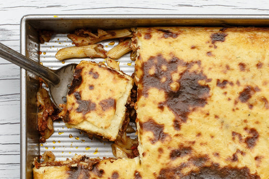 A baking dish filled with Greek Pastitsio with a slice being cut out and served.