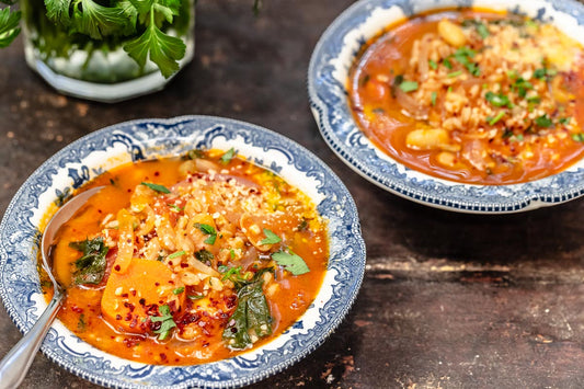 Two bowls filled with Tuscan farro soup and topped with fresh herbs.