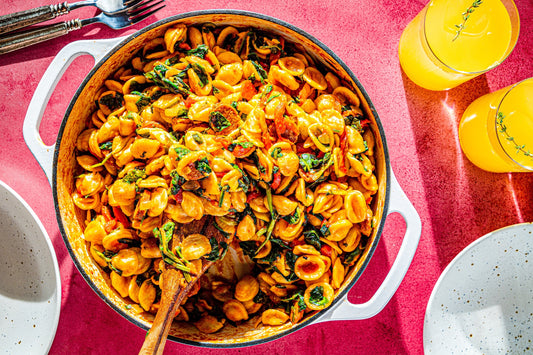 An overhead photo of a large bowl filled with orecchiette pasta with chorizo and topped with fresh herbs.