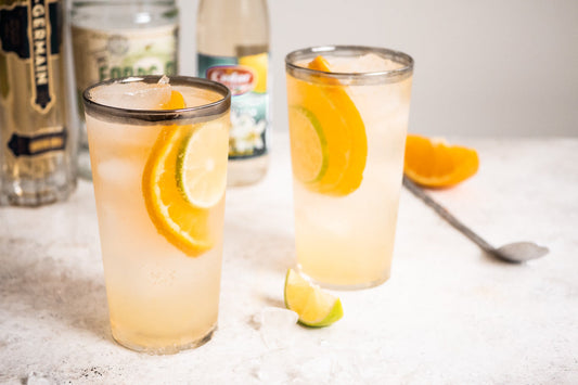 Two large cups filled with orange and lime wedges and bottles of alcohol in the back.