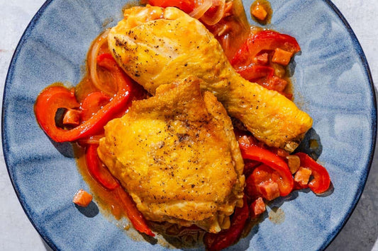 An overhead photo of a blue plate with a chicken thing and leg garnished with red peppers.