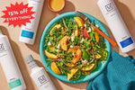 A styled flat-lay featuring a bowl of fresh salad with peach slices, greens, and crumbled cheese, surrounded by white bottles of The Mediterranean Dish olive oils. A red starburst overlay reads '15% off EVERYTHING'.
