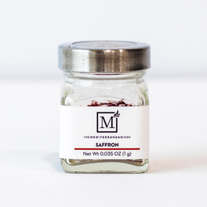 A small glass jar of The Mediterranean Dish saffron with a white label and a silver metal lid, photographed on a clean white background.