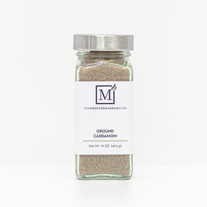 A glass spice jar filled with ground cardamom, featuring a white label with the brand logo 'The Mediterranean Dish' and a silver metal lid, set against a clean white background.